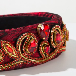 Close-up of red embroidery headband with sparkling ruby-colored gemstones and gold patterns