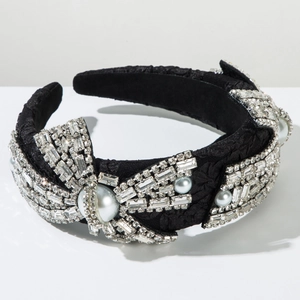 Dettaglio di un cerchietto nero con fiocco barocco, strass luccicanti e perle eleganti