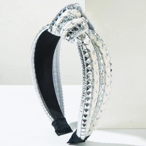 Close-up of white braided headband with silver metal studs and sparkling rhinestones