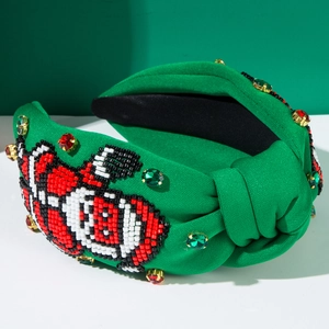 Détail de perles cousues main et strass sur un serre-tête de Noël vert noué