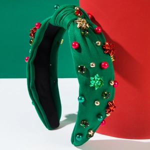 Dettaglio del cerchietto natalizio in maglia verde con perle e fiocchi regalo rossi