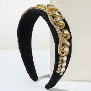 Close-up of golden embroidery and sparkling rhinestones on a black fabric headband