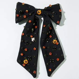 Détail d'un nœud papillon d'Halloween avec strass orange et pendentifs citrouille et fantôme