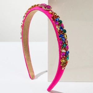 Détail d'un serre-tête en satin rose fuchsia orné de strass multicolores facettés