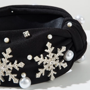 Gros plan du bandeau à nœud noir avec perles blanches et flocons de neige en strass