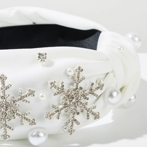 Détail d'un serre-tête en satin blanc avec flocons de strass et perles nacrées