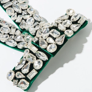 Detailed close-up of crystal rhinestones on dark green velvet luxury hair clip