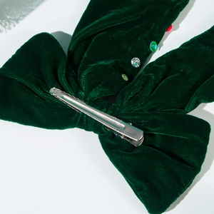 Dettaglio del fermaglio a fiocco in velluto verde scuro con paillettes e clip a coccodrillo