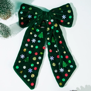 Dettaglio di fiocco natalizio in velluto verde con paillettes, fiocchi e mini alberi