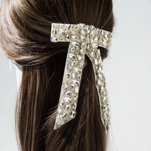 Macro detail of luxury rhinestone bow hair clip with multi-shaped crystals and velvet base