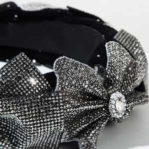 Close-up of sparkling rhinestones and crystal bow on black velvet headband