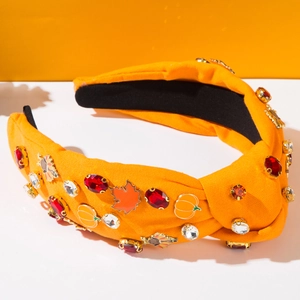 Détail d'un serre-tête noué orange avec breloques citrouille, érable et strass
