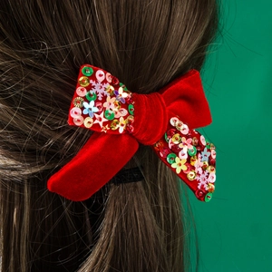 Fiocco di velluto rosso per Natale con paillettes scintillanti tra i capelli castani