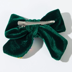 Dettaglio del fermaglio a fiocco in velluto verde scuro con clip a coccodrillo in metallo