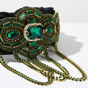 Dettaglio di un cerchietto di lusso con cristalli verde smeraldo e nappine di strass