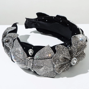 Detailed close-up of luxurious black velvet headband with sparkling rhinestone bows