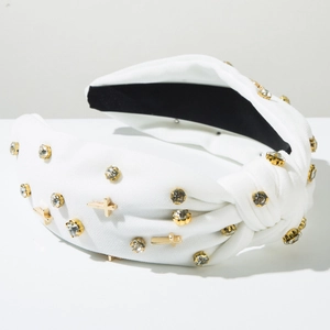 Detail of white knotted headband featuring sparkling rhinestones and golden metal crosses