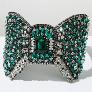 Macro view of crystal encrusted green bow headband with a large emerald cut centerpiece stone