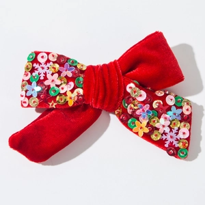 Dettaglio fiocco natalizio in velluto rosso con paillettes colorate e fiocchi di neve