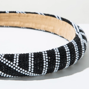 Close-up of padded headband featuring black beads and white pearls in wavy stripes