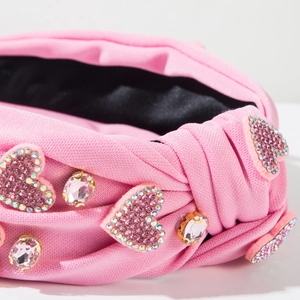 Détail d'un serre-tête rose noué avec des accents de cœur et des strass brillants