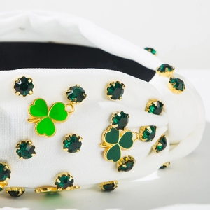 Détail de strass verts et charms trèfle dorés sur un serre-tête blanc irlandais