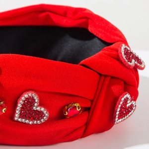 Détail du bandeau rouge noué avec des patchs en cœur strassés et un bijou cristal