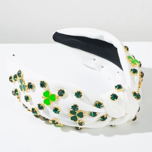 Détail de trèfle en strass vert et émail sur un serre-tête noué en tissu blanc