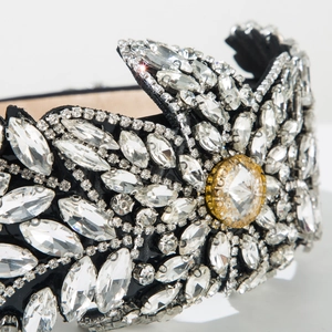 Détail d'un serre-tête noir de luxe orné de cristaux sertis main au motif floral radieux