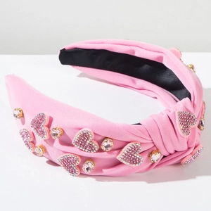 Gros plan d'un serre-tête noué rose avec strass en forme de cœur et texture tricotée