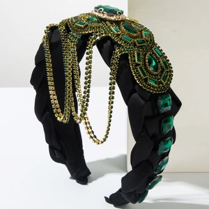 Dettaglio del cerchietto intrecciato nero con pietre preziose verde smeraldo e frange dorate