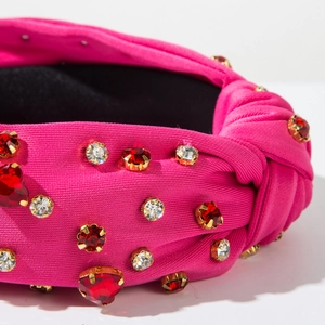 Detail of fuchsia knotted headband featuring glittering red rhinestones on knit fabric