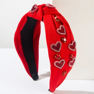 Détail du serre-tête rouge noué avec breloques cœurs en strass et gemmes rubis