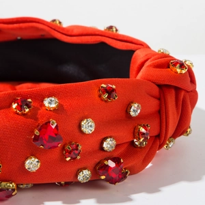 Close-up of red knotted headband with sparkling rhinestones and crystal heart detail