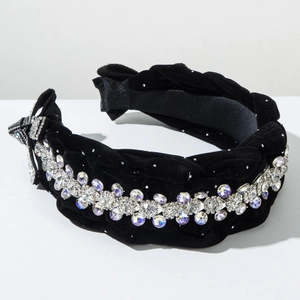 Dettaglio macro del cerchietto intrecciato in velluto nero con strass luccicanti e fiocco