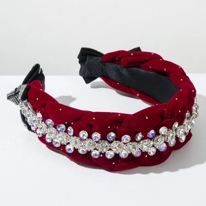 Dettaglio del cerchietto intrecciato in velluto rosso con strass a strati e fiocco nero
