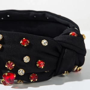 Close-up of black knot headband featuring sparkling red and clear crystals in gold claw settings