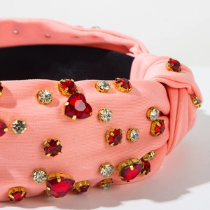 Detail of pink ribbed fabric headband with sparkling red heart-shaped rhinestones