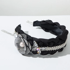 Detalle de diadema trenzada ancha con flor de pedrería, perla y adorno de mariposa