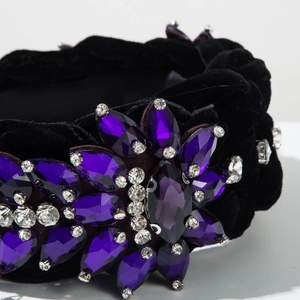 Macro shot of hand-stitched purple crystal embellishments on a black velvet headband