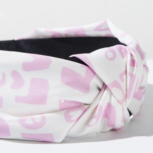 Close-up of white fabric headband with pink LOVE text print and center knot detail