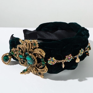 Détail d'un serre-tête tressé en velours vert avec métal doré baroque et gemmes émeraude