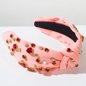 Detailed macro view of pink knotted headband with sparkling red heart-shaped rhinestones