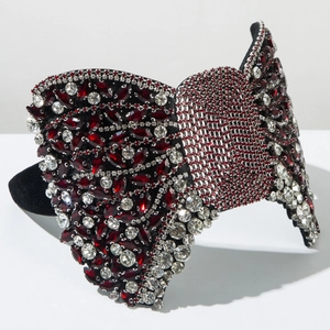 Vue détaillée des strass rouges et transparents sur un serre-tête nœud papillon noir