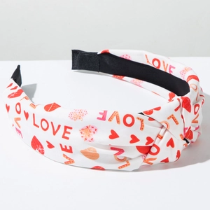 Detail showing knotted fabric headband with LOVE text and heart patterns on white background
