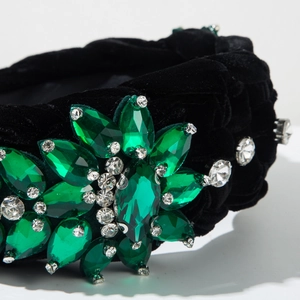 Macro detail of hand-stitched green crystals and white rhinestones on black velvet headband