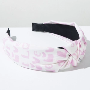 Detail of white knot headband with pink LOVE lettering and romantic heart prints