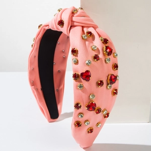 Detail of pink knitted knotted headband with red heart crystals and sparkling rhinestones