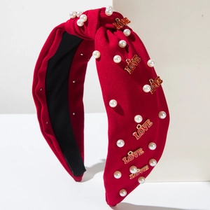 Serre-tête rouge à nœud avec perles et breloques LOVE dorées sur présentoir