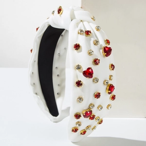 Detail of white knit headband with red heart crystals and golden rhinestone settings